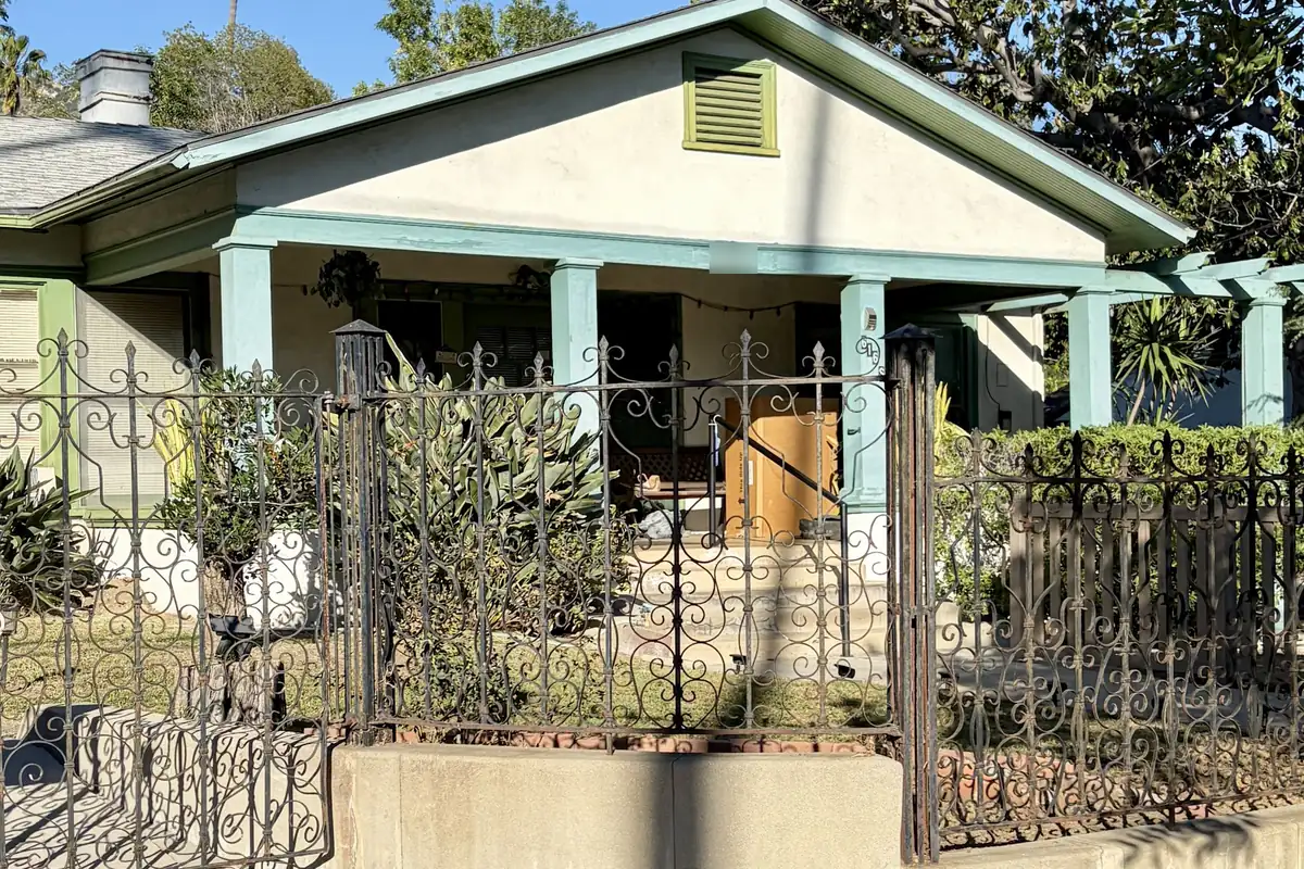 Bungalow on South Bel Aire Drive in Burbank behind a low concrete wall and iron fence